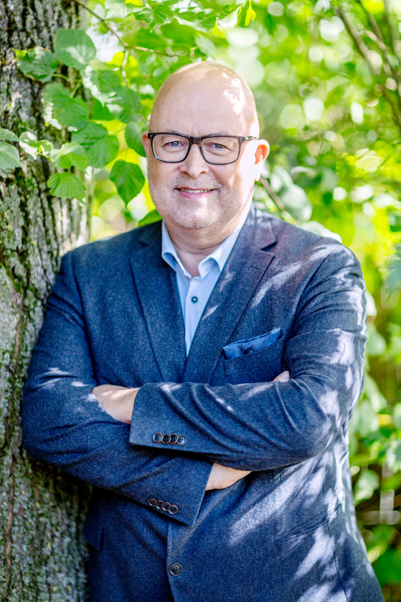 Norbert Peter mit verschränkten Armen an einem Baum